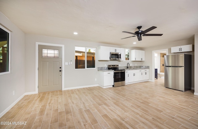 kitchen with ceiling fan, light stone countertops, white cabinetry, and stainless steel appliances