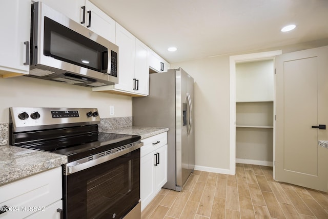 kitchen featuring white cabinets, stainless steel appliances, and light stone counters