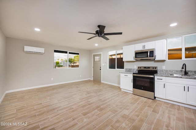 kitchen with white cabinets, a wall unit AC, sink, and appliances with stainless steel finishes