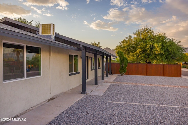 property exterior at dusk featuring a patio and cooling unit