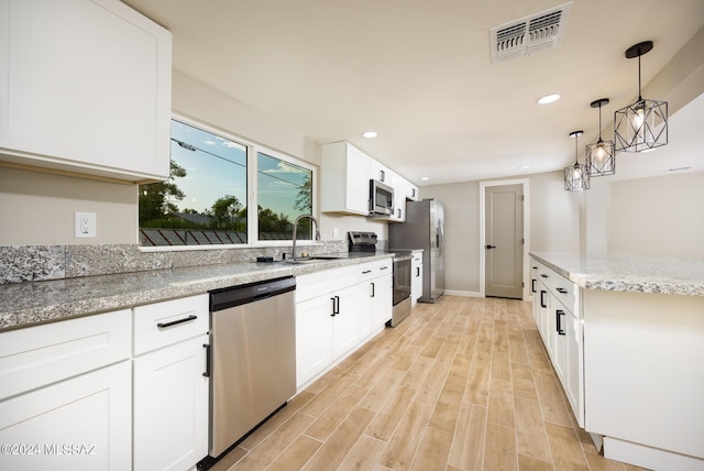 kitchen with sink, light hardwood / wood-style floors, decorative light fixtures, white cabinets, and appliances with stainless steel finishes