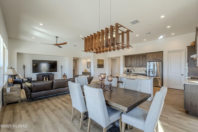 dining room featuring ceiling fan, light wood-type flooring, and sink