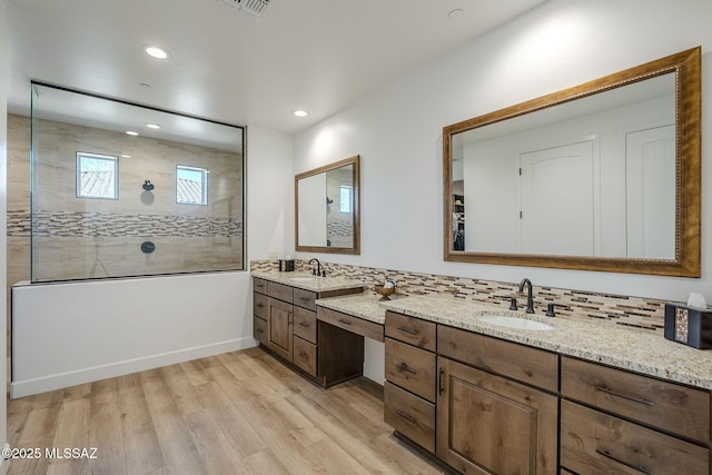 bathroom with decorative backsplash, wood-type flooring, vanity, and a tile shower