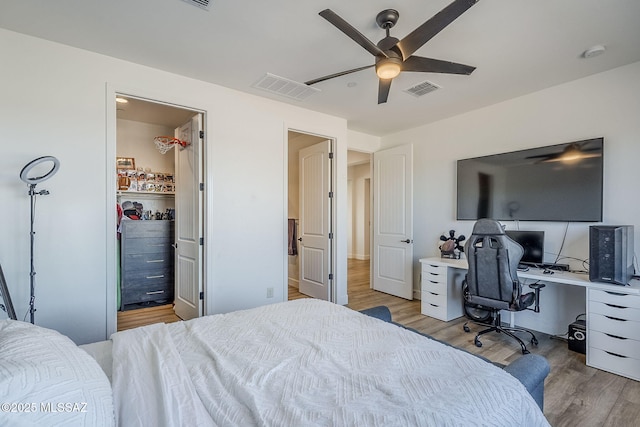 bedroom with ceiling fan, a closet, a spacious closet, and light hardwood / wood-style floors