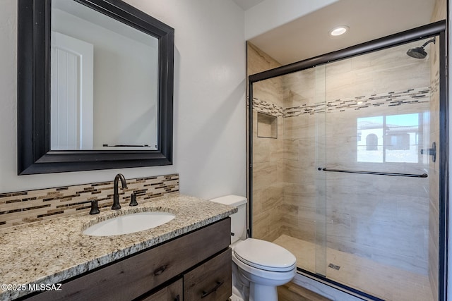 bathroom with toilet, walk in shower, backsplash, and vanity