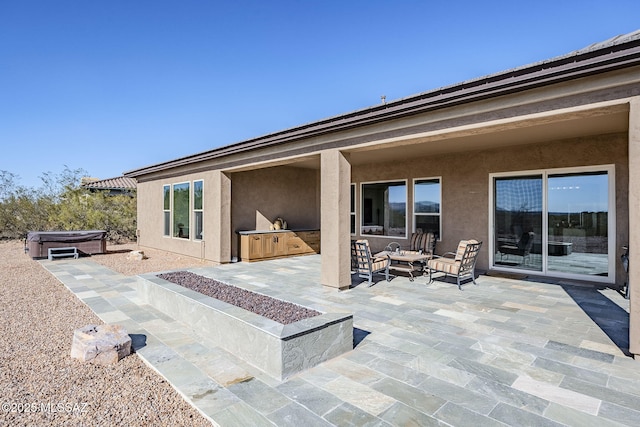 exterior space with an outdoor living space with a fire pit, an outdoor kitchen, and a hot tub