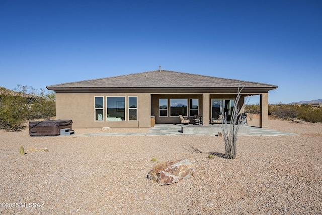 rear view of house with a patio area and a hot tub