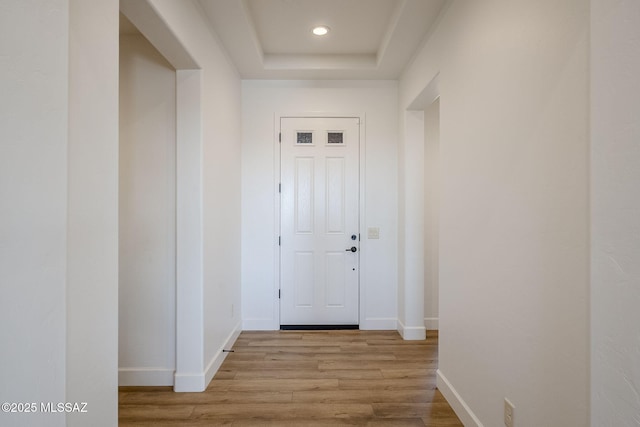 doorway to outside featuring light hardwood / wood-style floors and a tray ceiling