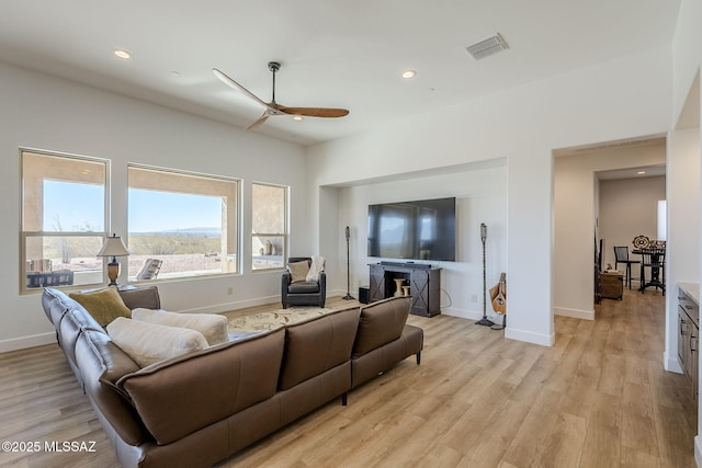 living room with ceiling fan, a fireplace, and light hardwood / wood-style floors