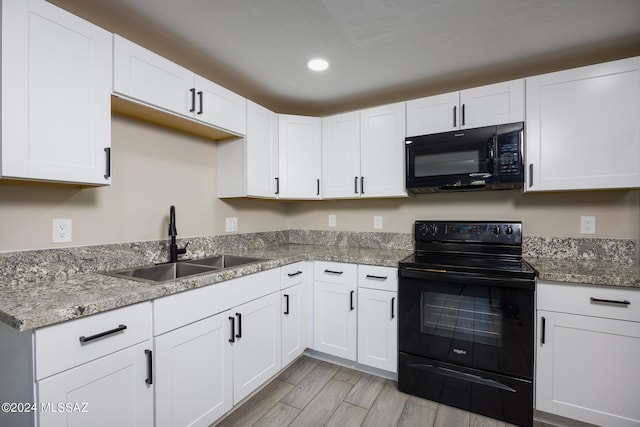 kitchen with black appliances, white cabinets, light stone countertops, and sink