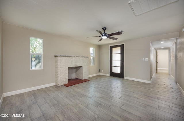 unfurnished living room featuring a fireplace, light wood-type flooring, and ceiling fan