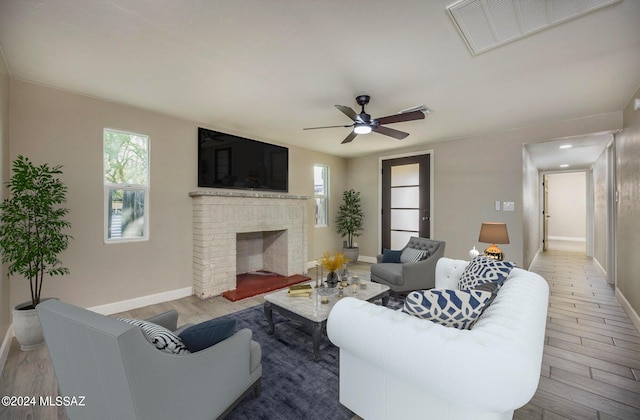 living room with hardwood / wood-style flooring, ceiling fan, and a fireplace