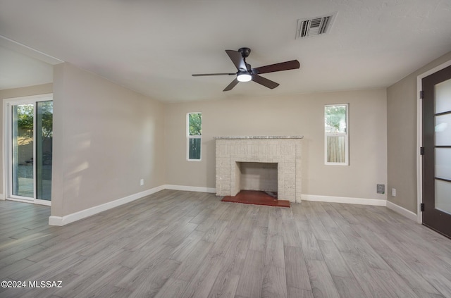 unfurnished living room with a wealth of natural light, light hardwood / wood-style flooring, a brick fireplace, and ceiling fan