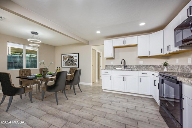 kitchen featuring white cabinetry, sink, light stone countertops, hanging light fixtures, and black appliances