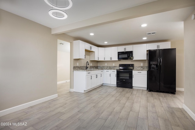 kitchen with light stone counters, white cabinets, and black appliances