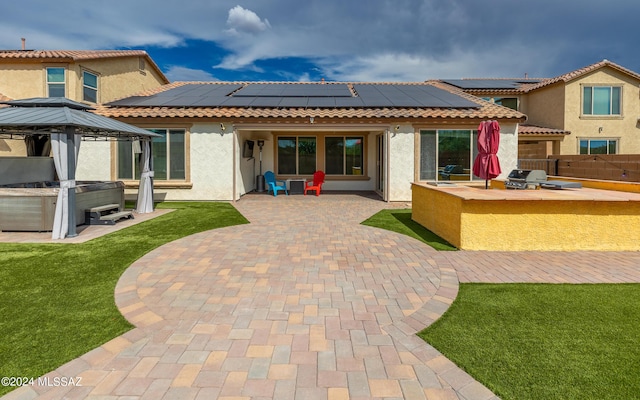 rear view of house with a gazebo, a patio, and a hot tub