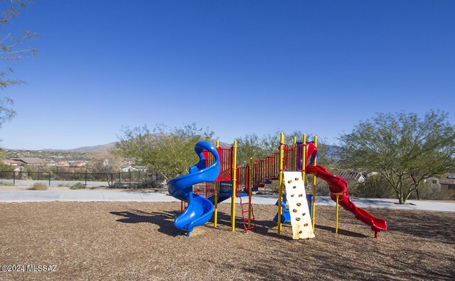 community jungle gym featuring a mountain view and fence