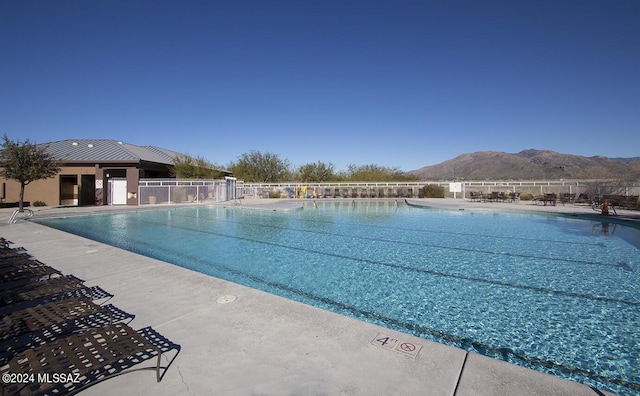 pool with a patio area, a mountain view, and fence