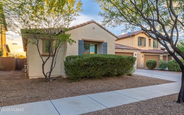 mediterranean / spanish-style house featuring concrete driveway, stucco siding, fence, and a tile roof