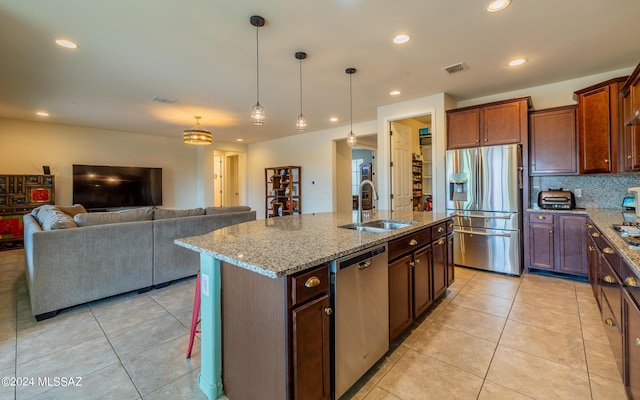 kitchen featuring light tile patterned flooring, a kitchen island with sink, sink, and appliances with stainless steel finishes