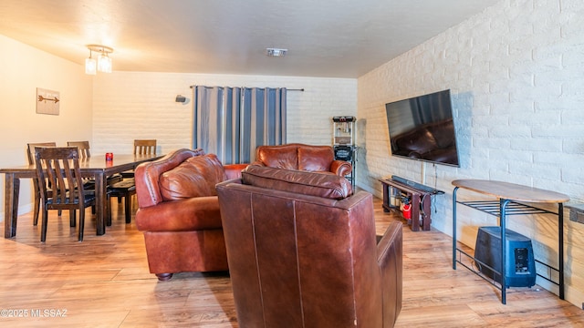 living room featuring light hardwood / wood-style flooring and brick wall