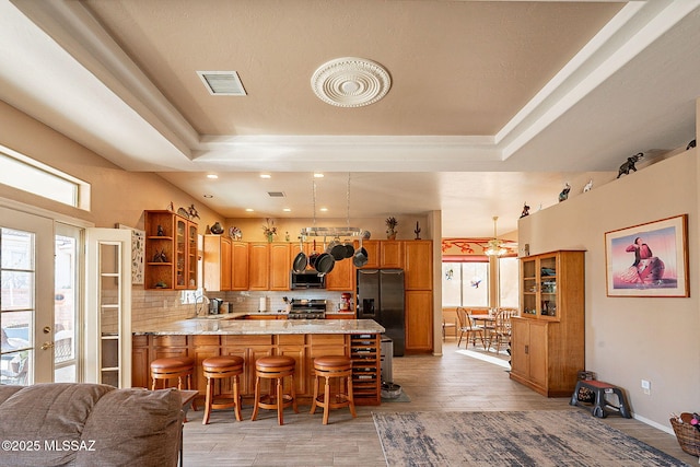 kitchen with kitchen peninsula, plenty of natural light, stainless steel appliances, and decorative light fixtures