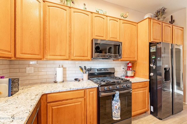 kitchen with tasteful backsplash, light stone counters, and stainless steel appliances