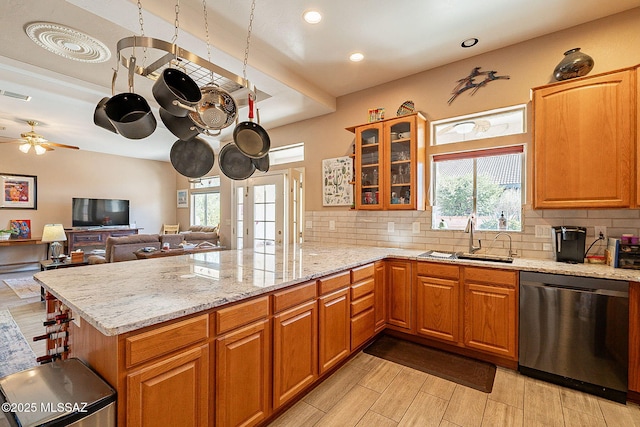 kitchen featuring dishwasher, sink, ceiling fan, light stone countertops, and kitchen peninsula