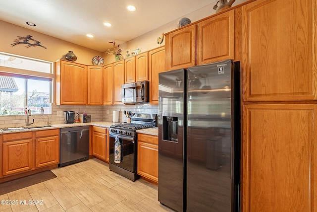 kitchen with decorative backsplash, appliances with stainless steel finishes, light stone countertops, and sink