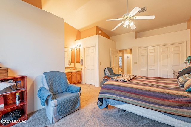 carpeted bedroom with ceiling fan, a closet, ensuite bathroom, and vaulted ceiling