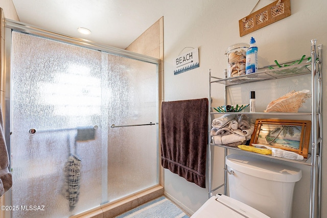 bathroom featuring a shower with door and toilet