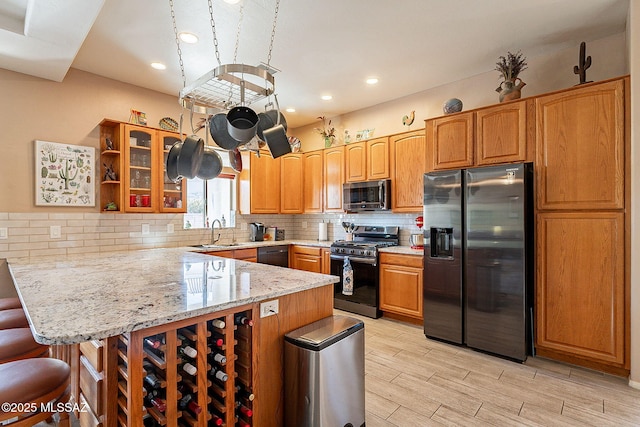 kitchen featuring black appliances, a kitchen breakfast bar, sink, decorative backsplash, and kitchen peninsula