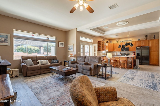 living room with a raised ceiling and ceiling fan