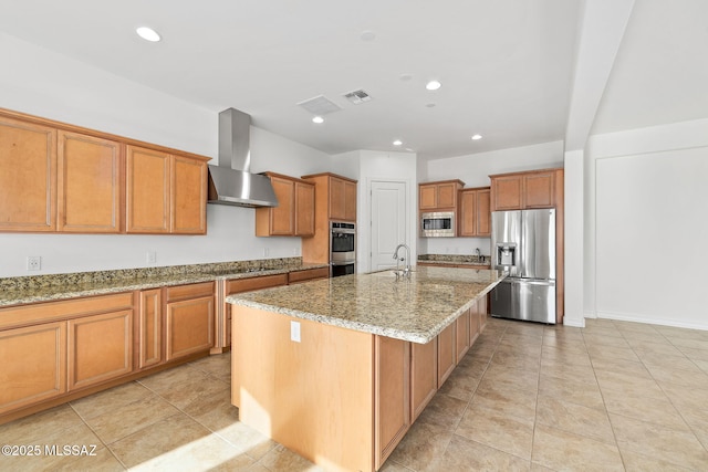 kitchen featuring light stone countertops, sink, wall chimney exhaust hood, a center island with sink, and appliances with stainless steel finishes