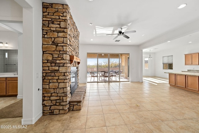 unfurnished living room featuring a stone fireplace, ceiling fan, and light tile patterned flooring