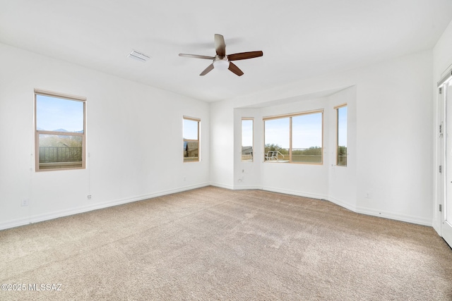 empty room with light carpet, ceiling fan, and a healthy amount of sunlight