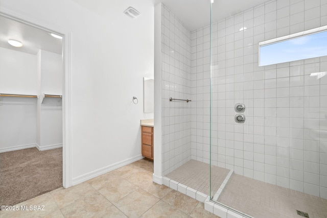 bathroom featuring tile patterned flooring, vanity, and tiled shower