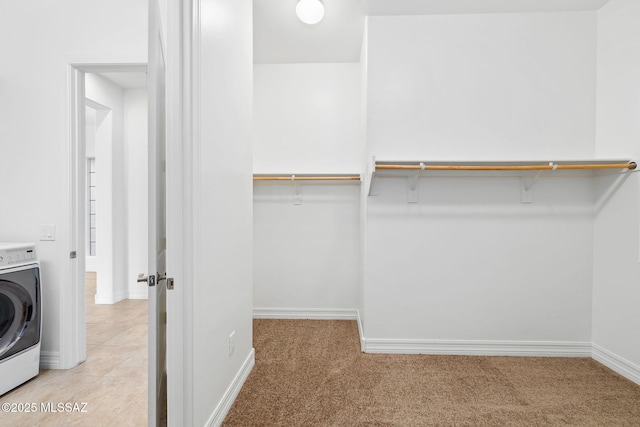 walk in closet featuring washer / dryer and light colored carpet