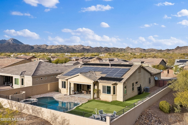 rear view of house featuring solar panels, central AC unit, a patio area, a mountain view, and a fenced in pool