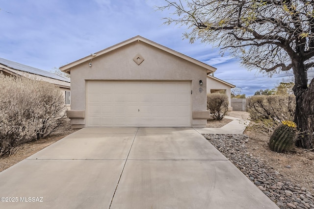 view of front of property featuring concrete driveway, an attached garage, and stucco siding