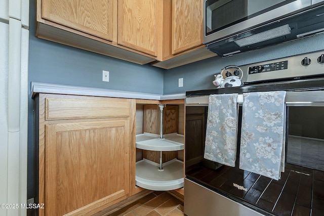 kitchen with light brown cabinets, stainless steel microwave, and oven