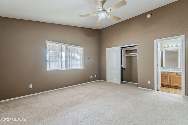 unfurnished bedroom featuring a closet, light colored carpet, ensuite bathroom, ceiling fan, and baseboards