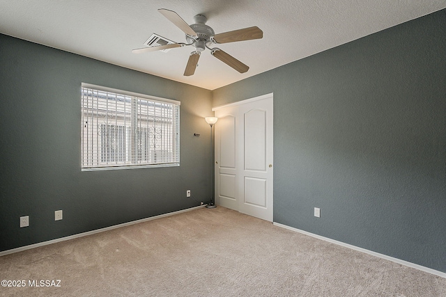 spare room with carpet floors, baseboards, visible vents, and ceiling fan