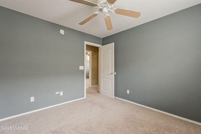 unfurnished room featuring a ceiling fan, light carpet, and baseboards