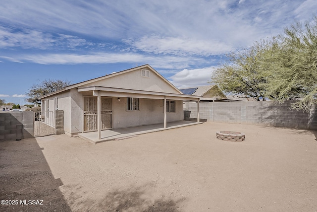 rear view of property featuring a gate, a fenced backyard, a patio, and stucco siding