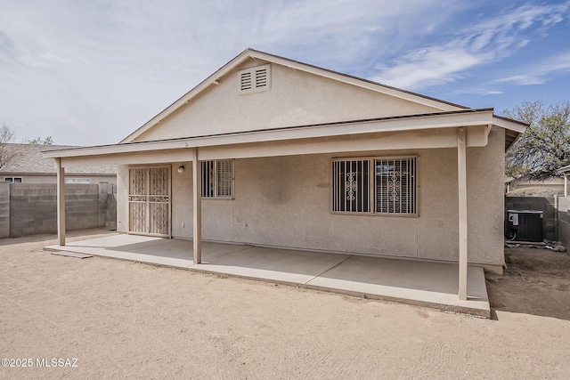 rear view of property with a patio area, fence, central AC, and stucco siding