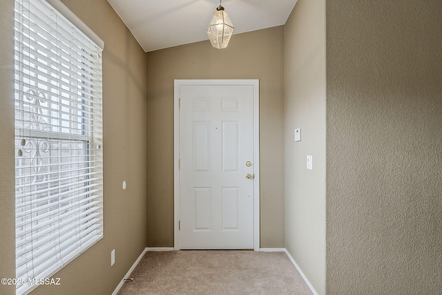 doorway featuring baseboards and light colored carpet