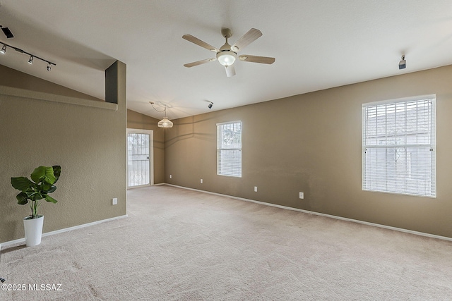 carpeted empty room featuring vaulted ceiling, ceiling fan, and baseboards