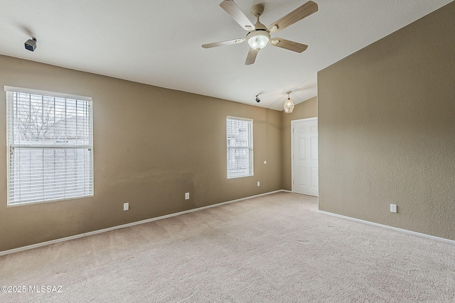 spare room featuring a textured wall, light carpet, vaulted ceiling, ceiling fan, and baseboards