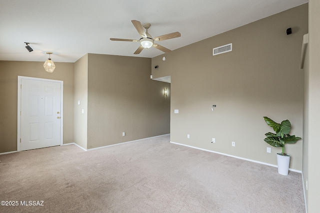 spare room featuring a ceiling fan, light colored carpet, visible vents, and baseboards